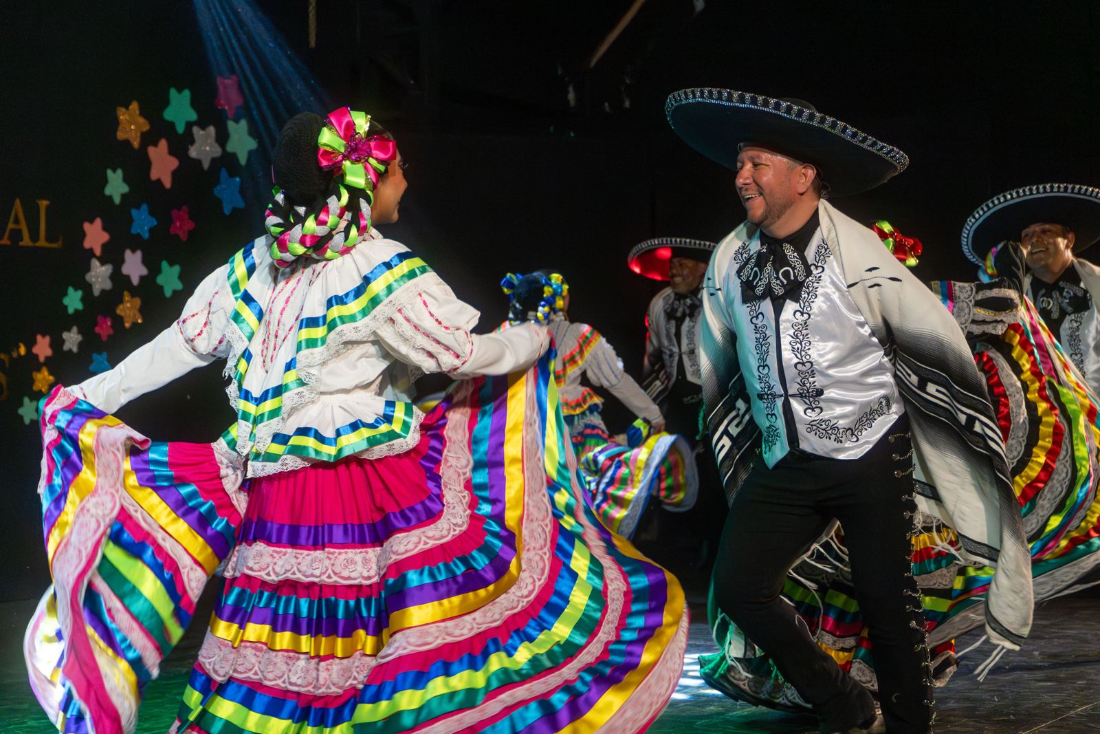 Pareja de baile con trajes coloridos girando en el escenario