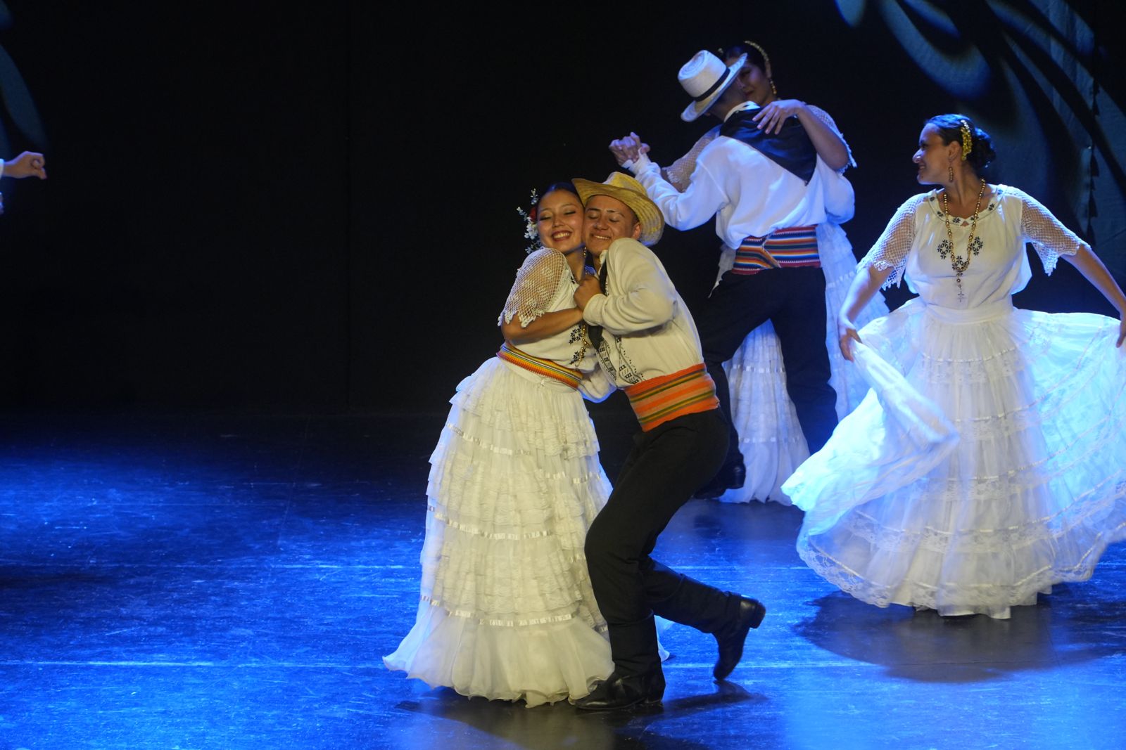 Bailarines con vestidos blancos tradicionales en el escenario